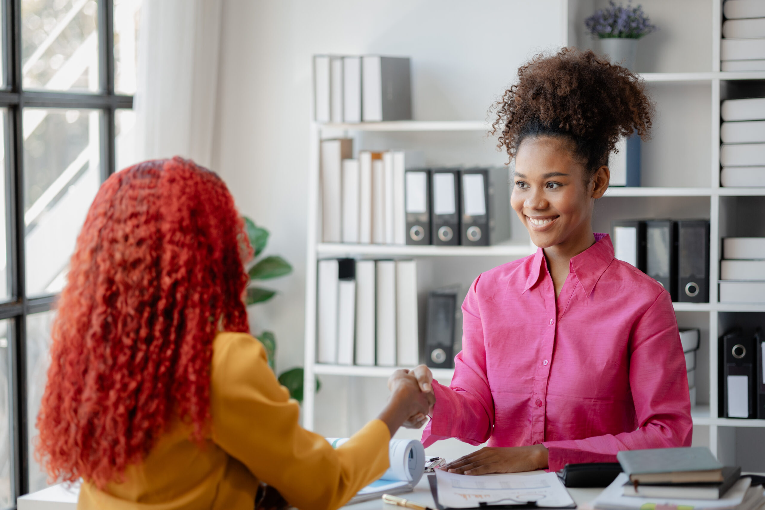 Two beautiful African female were shaking hands in the office as important work has been discussed successfully, beautiful successful African businesswomen are holding hands due to business victory.